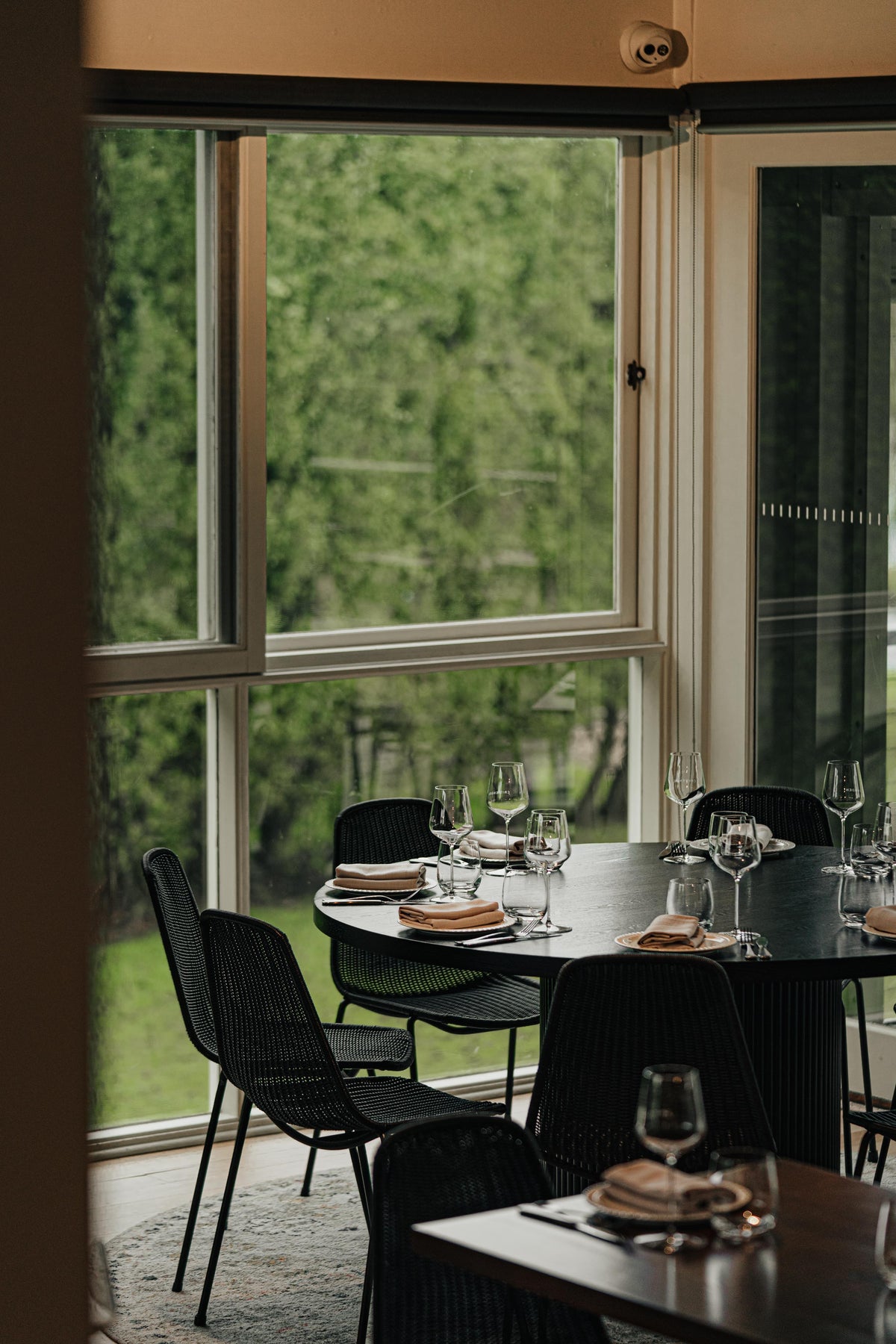 Restaurant tables set by tall windows looking onto the garden