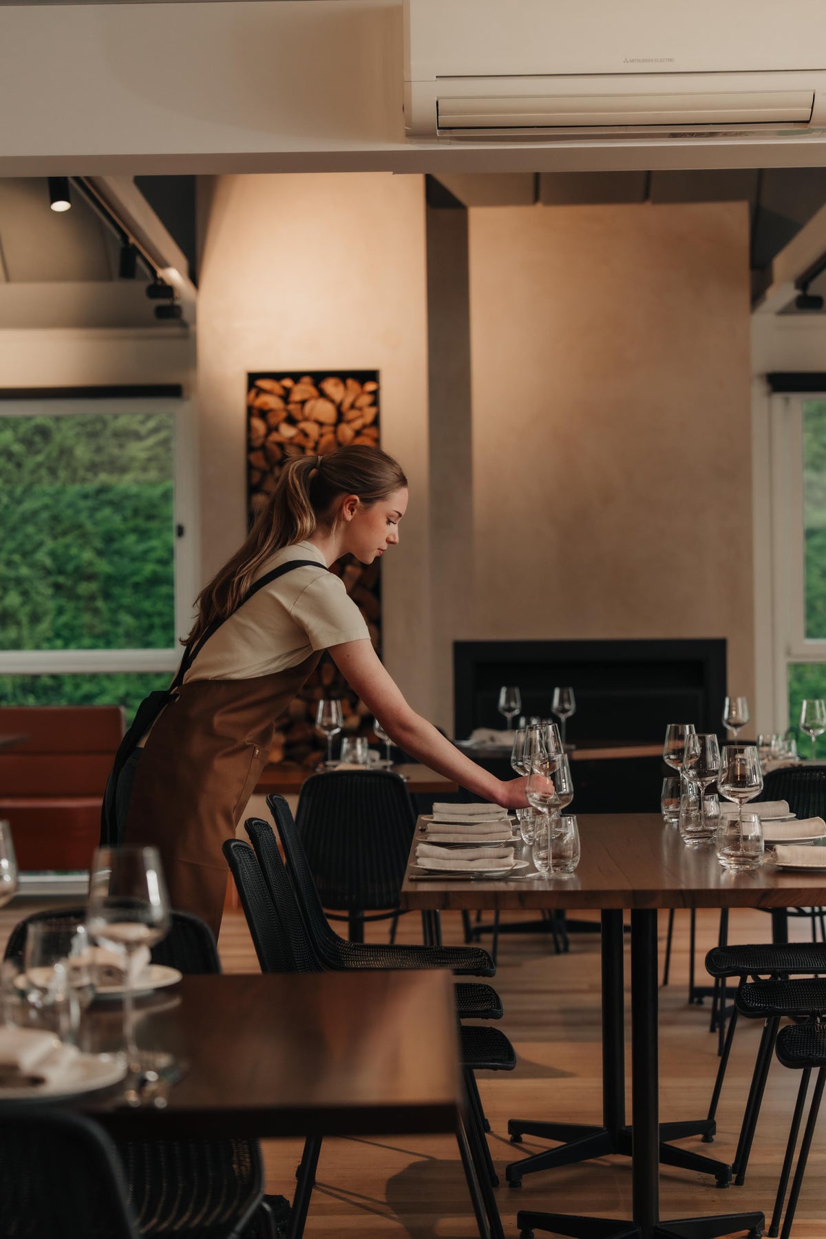 A server setting restaurant tables by the fireplace