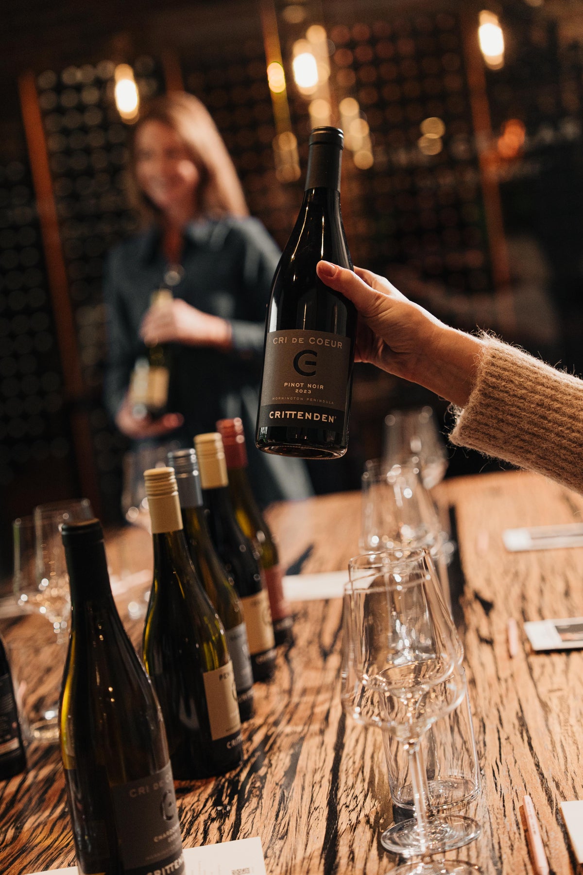 A host holding up a bottle at a seated tasting