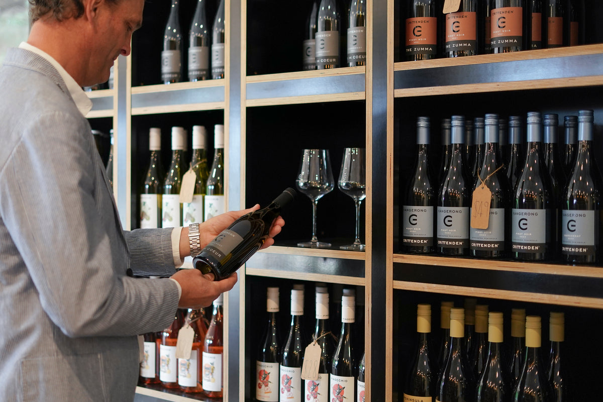 A guest choosing a bottle from the cellar door shelves