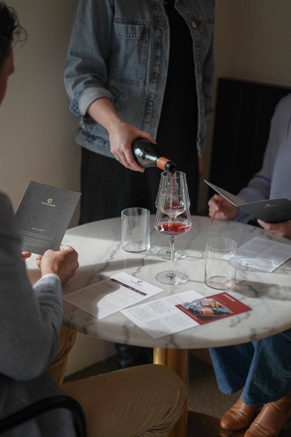 A host pouring a tasting for guests at a marble table