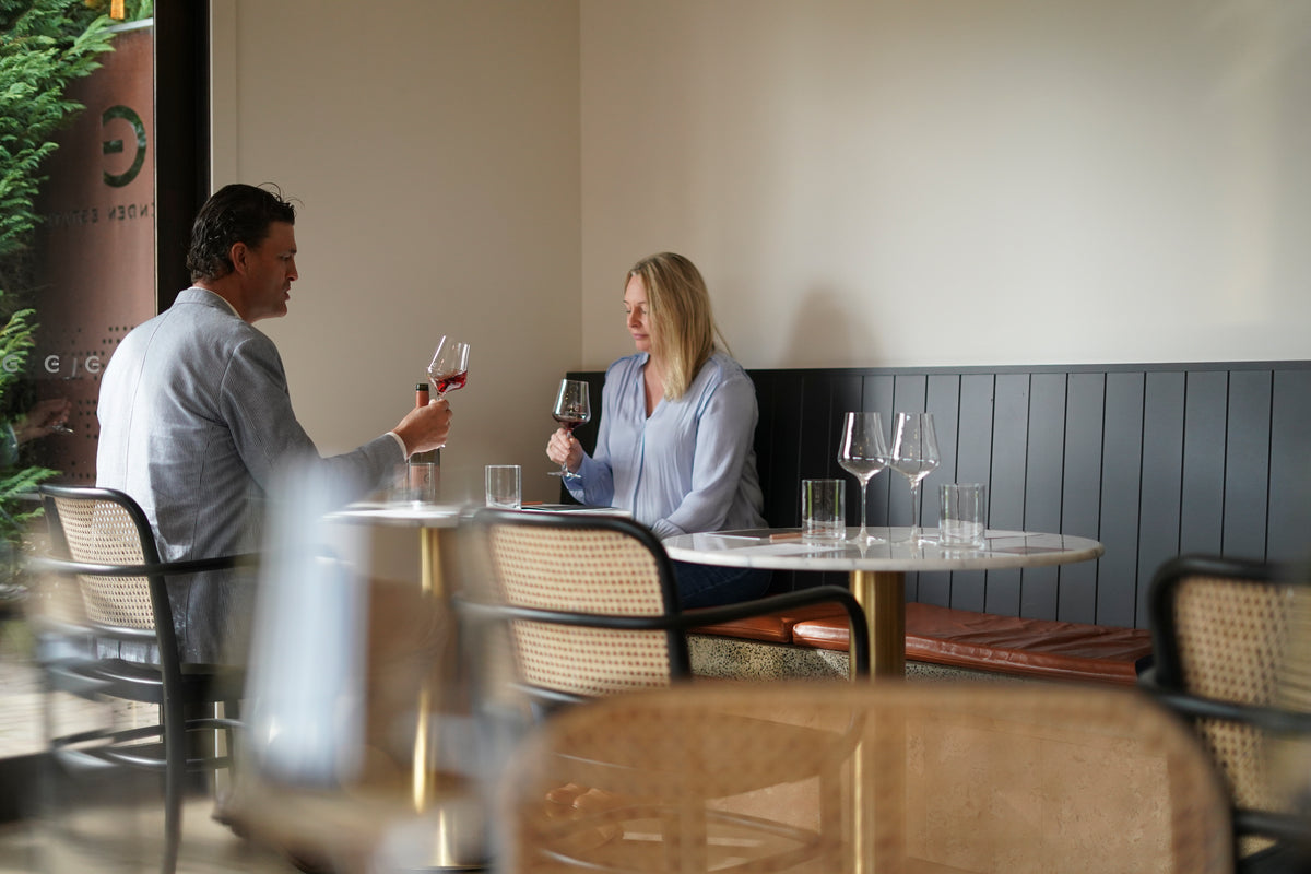 Two guests tasting red wine at a cellar door table