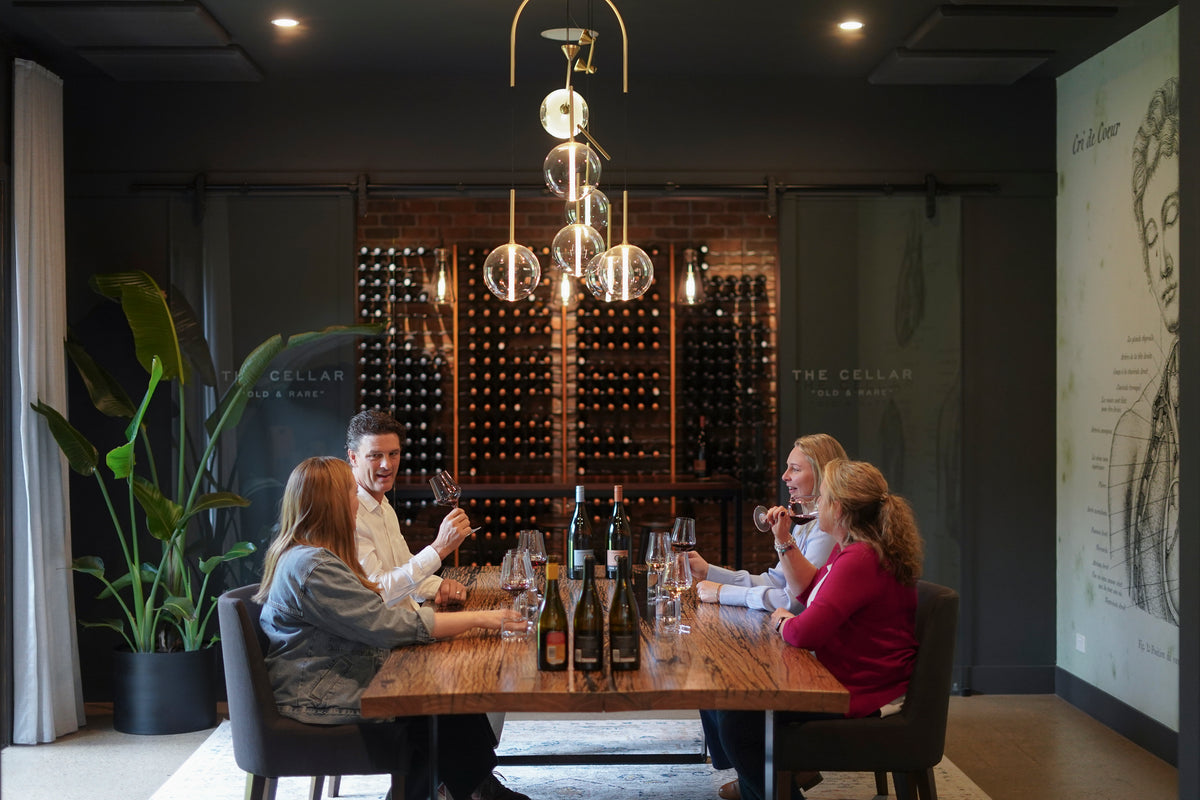 Guests at a seated tasting beside the wine wall