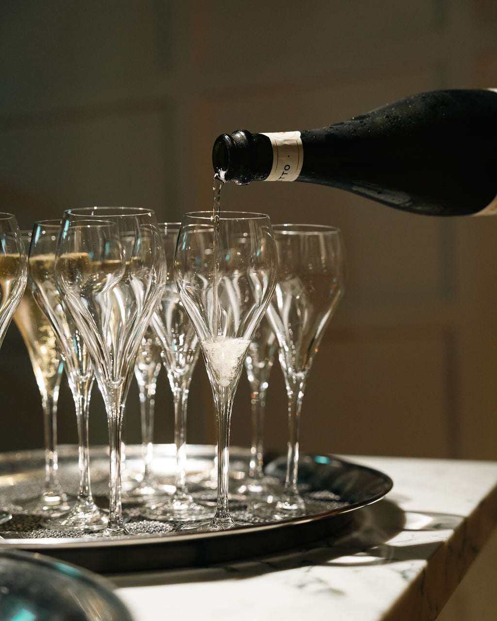 Sparkling wine being poured into a tray of flutes