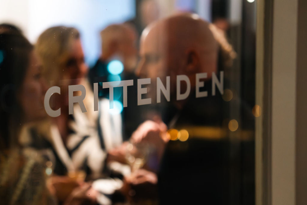 Guests at an evening function seen through glass etched with the Crittenden name