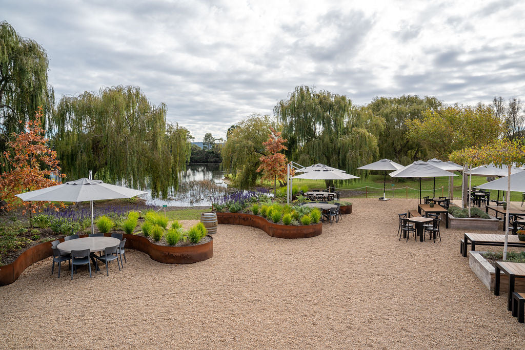 The Terrace's gravel courtyard with tables, umbrellas and the lake