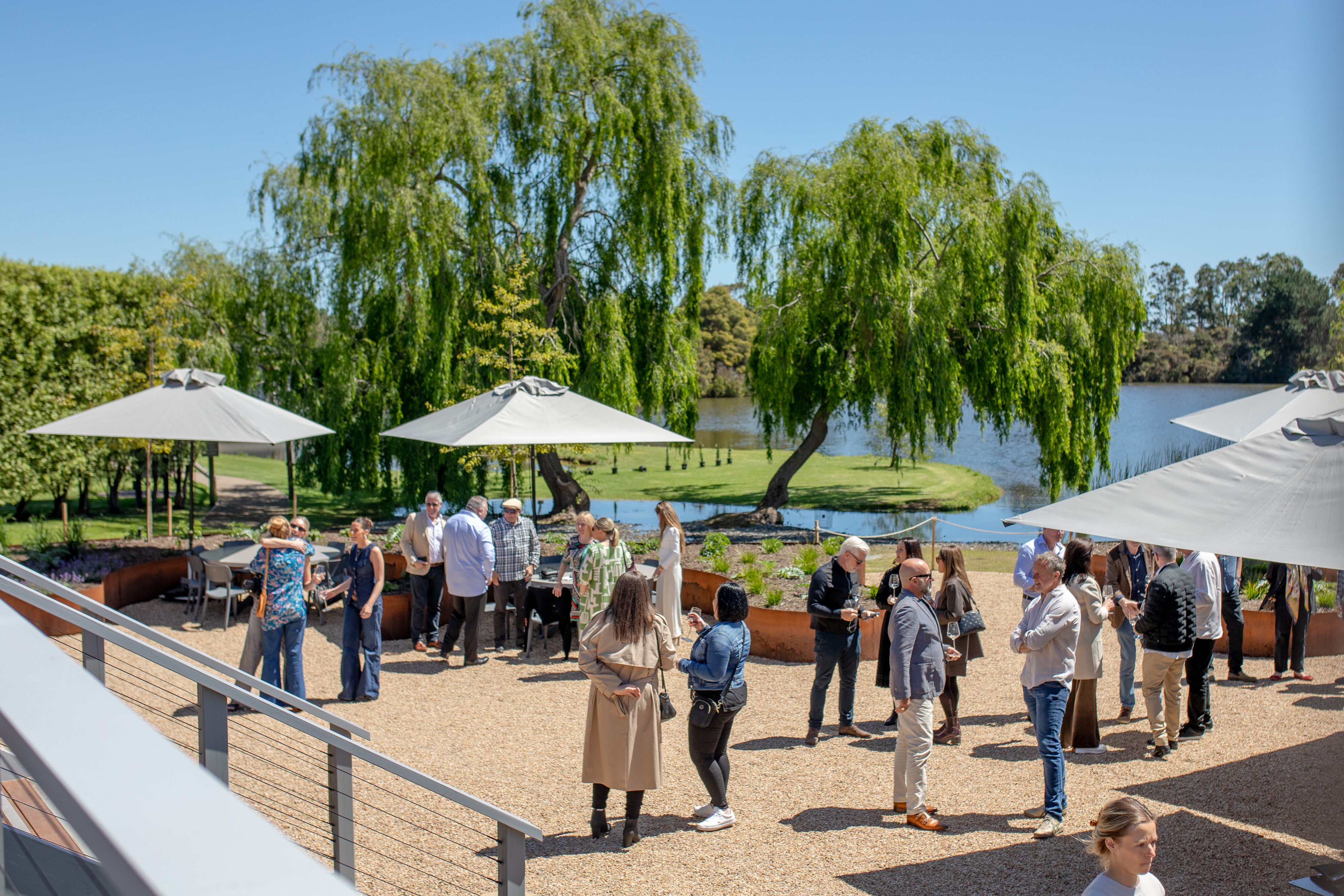 A crowd at a lakeside event on the Terrace, with willows and umbrellas