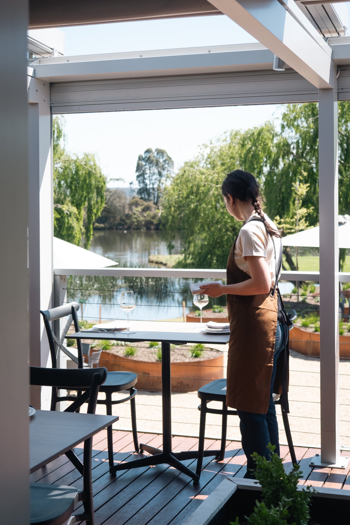 A server setting a table on the deck overlooking the lake