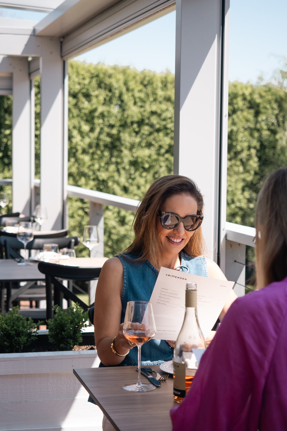 Two guests reading the menu over rosé on the deck
