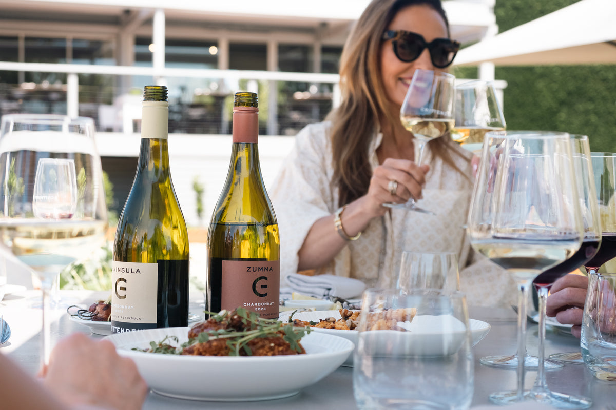 A guest with a glass of white wine and two bottles of Crittenden on the table
