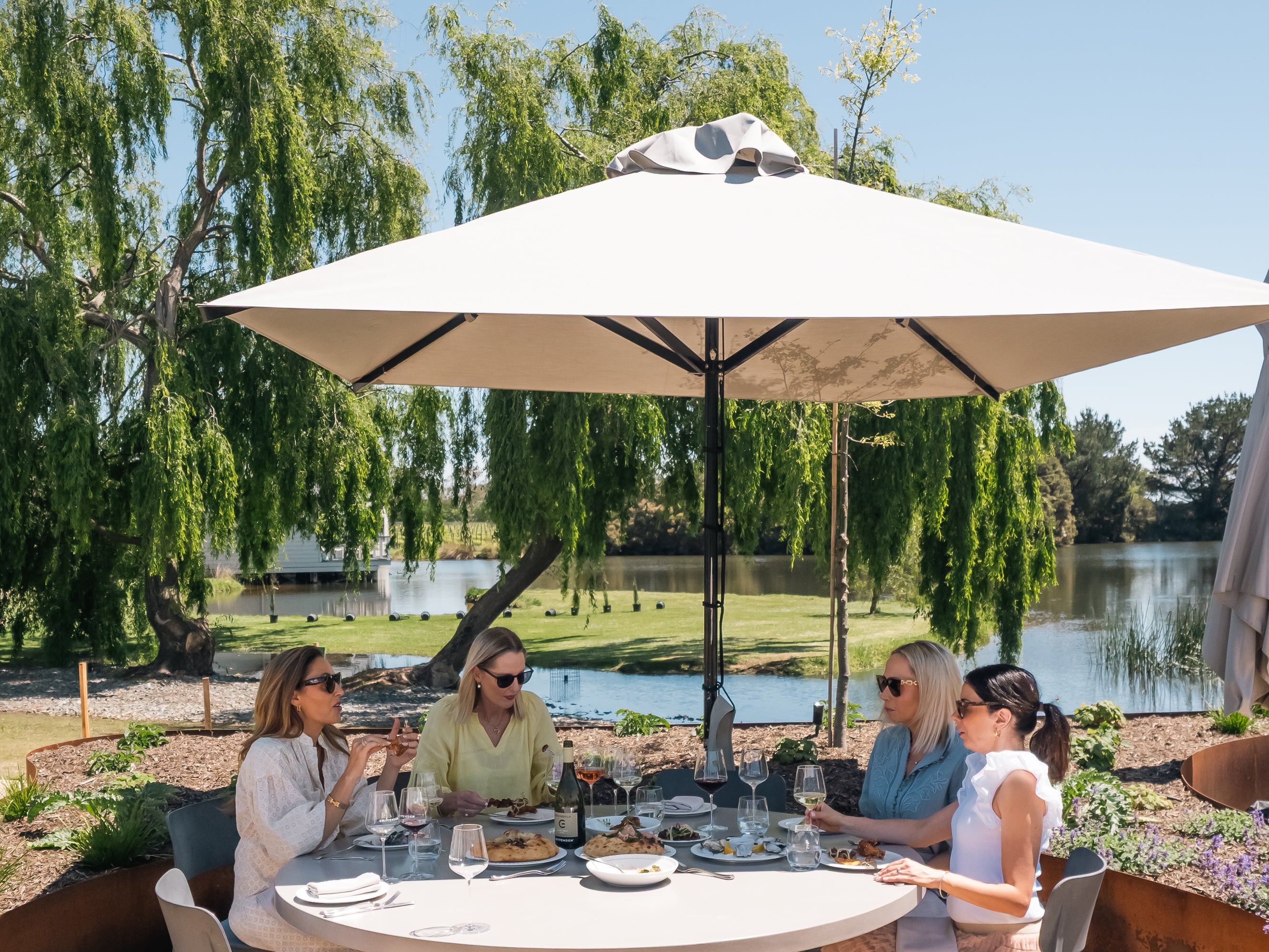 Guests lunching under an umbrella on the Terrace by the lake