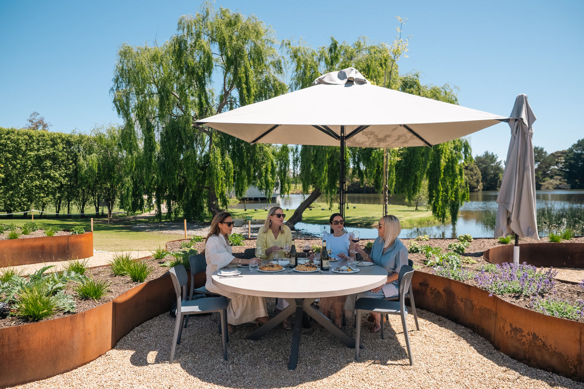 Friends lunching under a large umbrella on the Terrace by the lake
