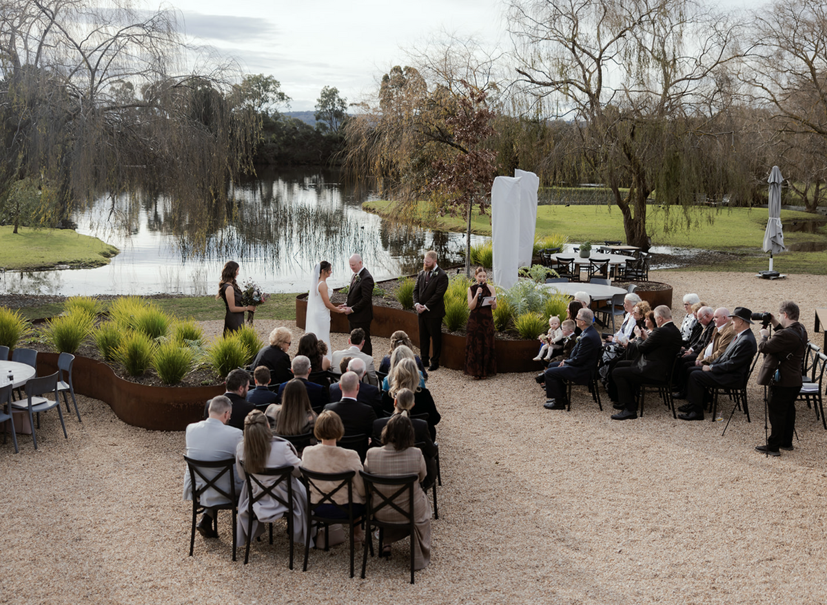 A wedding ceremony with seated guests by the lake
