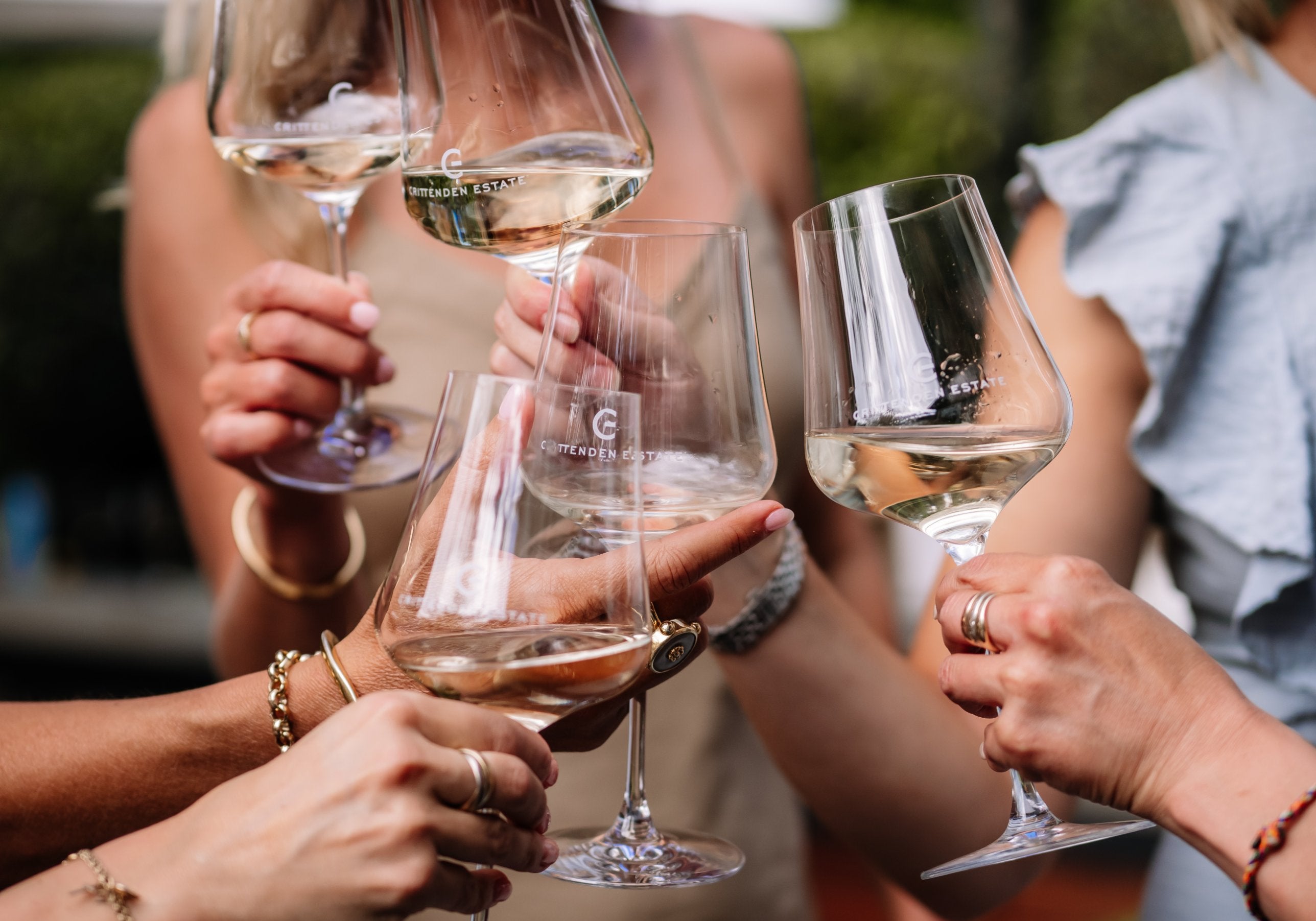 Friends raising glasses of white wine in Crittenden Estate glasses