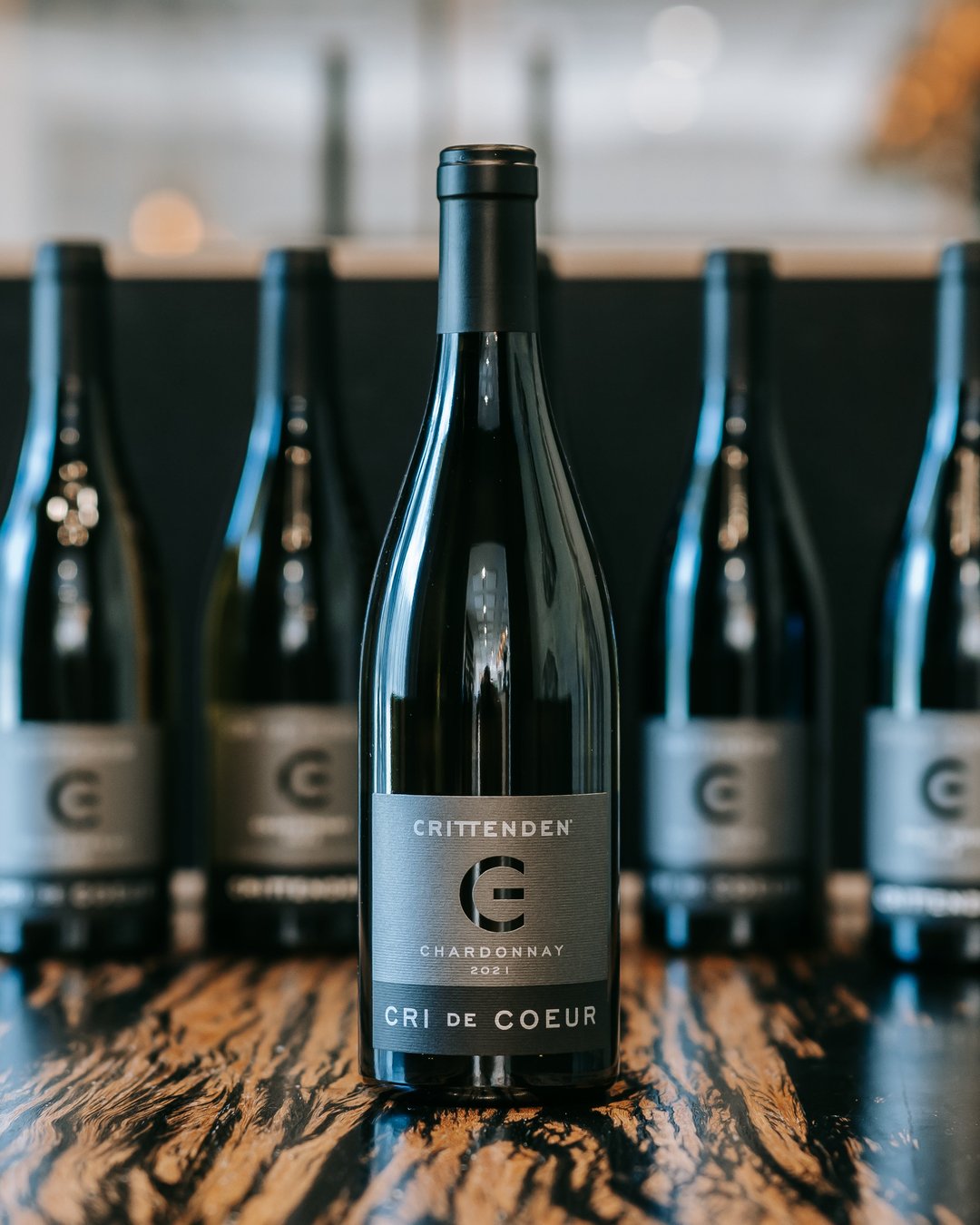 A bottle of 2021 Cri de Coeur Chardonnay in front of a row of matching bottles